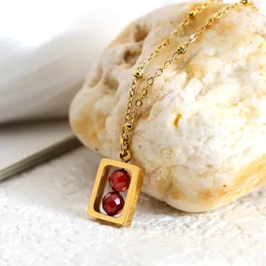 Minimalistische gouden titanium stalen ketting met rechthoekig frame en rode zirkonia kralen