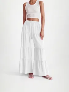 Detail shot of women's white tiered wide-leg pants with crinkled texture and elastic high waist.