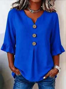 Blue V-neck blouse detail featuring large wooden buttons and elegant ruffle sleeves.