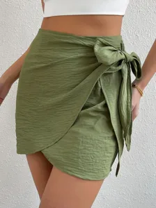Minifalda cruzada verde de talle alto con elegante lazo lateral y dobladillo irregular.