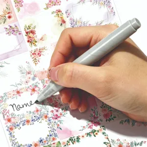 Primer plano de mano escribiendo en etiquetas de nombre florales impermeables con rotulador