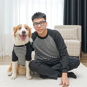 Detail shot of matching black and white striped pet and owner outfits in a cozy home indoor setting.