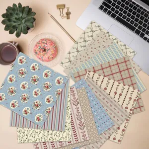 Flat lay of 13 vintage floral and geometric patterned scrapbook papers on a desk