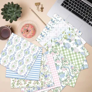 A diverse set of 13 floral and patterned scrapbook papers arranged on a creative desk setup