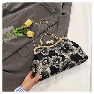 Close-up of vintage floral embroidery clutch with pearl clasp and gold chain