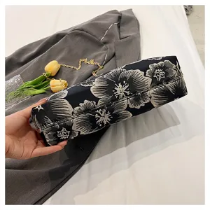 Close-up of bottom stitching on a black floral embroidered handbag with golden chain straps