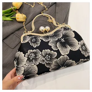Detail view of the intricate floral embroidery and gold handle on this vintage handbag.