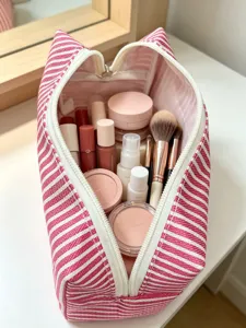 Rosa gestreifte Kosmetiktasche aus Leinen im Detail mit geräumigem Innenraum voll Kosmetik.