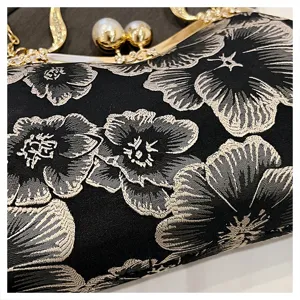 Close-up detail of exquisite floral embroidery and pearl-accented gold frame on evening bag