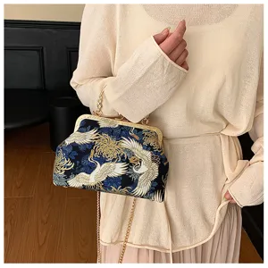 Dettaglio del ricamo della gru e della chiusura vintage sulla borsa a conchiglia
