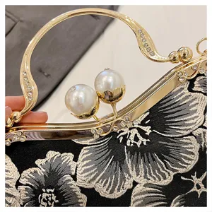Detailed view of handmade floral embroidery and pearl clasp on a Chinese style clutch bag.