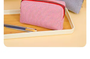 Detailed shot of the red and white striped makeup pouch, showing the clean zipper and fabric.