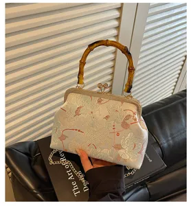 Dettaglio di una borsa ricamata in stile cinese moderno con manico in bambù.