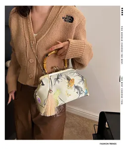 Primer plano del bolso de seda crema estilo Qipao con bordado y asa de bambú natural