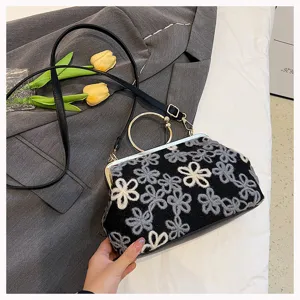 Detail of retro velvet handbag with elegant floral embroidery and gold metal handle.