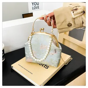Detail view of a vintage light blue silk handbag with pearl handle and floral pattern