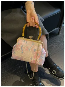 Dettaglio di una borsa a conchiglia ricamata rosa con manico in bambù e catena