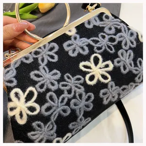Close-up of retro black velvet handbag with floral embroidery and golden round handle