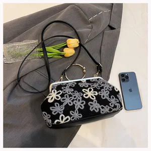 Vintage velvet handbag with floral embroidery and circular metal handle detail.
