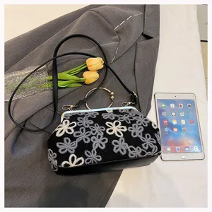 Vintage velvet handbag with floral embroidery and metal ring handle on grey blazer