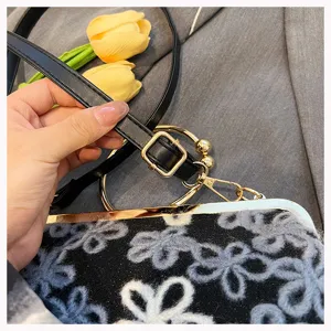 Detail showing adjustable strap and golden ring handle of a sequined floral velvet bag