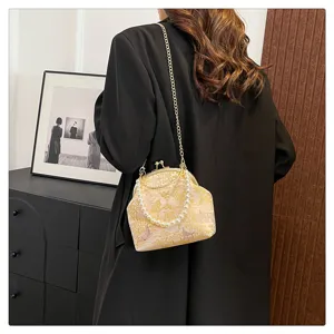 Elegant silk brocade handbag with pearl handle and chain strap worn over a black coat