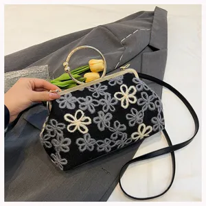 Close-up of vintage velvet handbag with elegant floral embroidery and gold ring handle