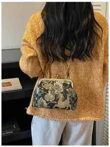 Dettaglio di una borsa a conchiglia ricamata con fiori e manico in bambù vintage