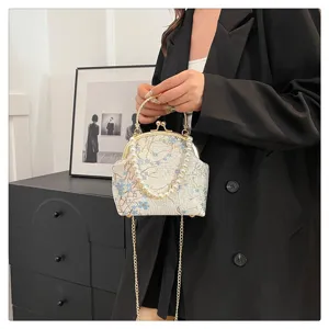 Detailed view of a vintage-style silk handbag with pearl handle and floral embroidery.