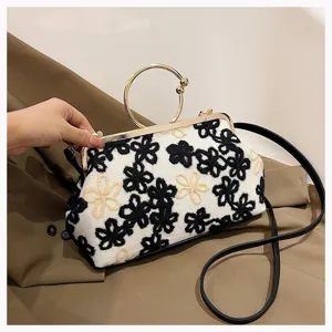 Detailed macro view of vintage evening handbag featuring black and white floral embroidery.