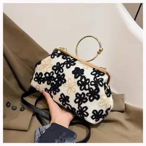 Detailed shot of a vintage floral embroidered velvet handbag with a gold ring handle