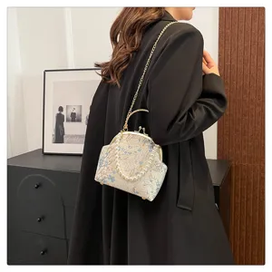 Detail view of a floral silk crossbody bag with pearl handle and gold chain strap