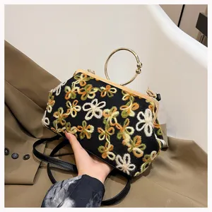 Detailed view of a vintage floral embroidered velvet handbag with a gold circular handle