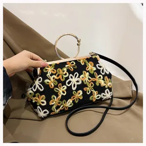 Close-up of vintage floral embroidery velvet handbag with golden ring handle detail