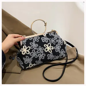 Close-up of vintage velvet evening bag with floral embroidery and gold metal handle