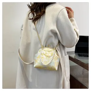Detail of vintage floral silk crossbody bag with elegant pearl handle and gold chain strap