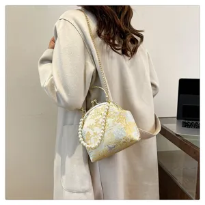 Detail showing silk floral embroidery and pearl handle of a vintage crossbody bag