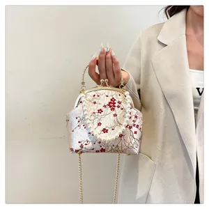 Detailed view of a vintage silk handbag featuring red floral embroidery and a pearl handle