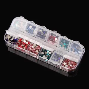 Gros plan d'une boîte de rangement transparente à 12 grilles remplie de strass d'ongles colorés.