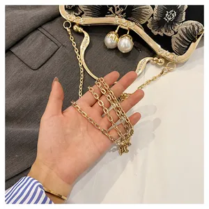 Close-up detail of the gold chain strap and pearl clasp on a black embroidered vintage bag