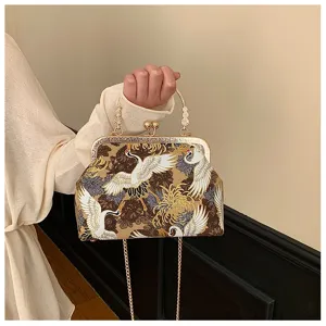 Dettaglio di borsa ricamata vintage con motivi di gru e chiusura a scatto in metallo