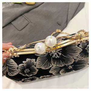 Close-up of elegant floral embroidered clutch with decorative pearl clasps