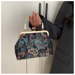 Vista dettagliata di un'elegante borsa a conchiglia ricamata con chiusura a scatto dorata.