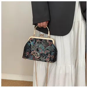 Dettaglio di borsa ricamata stile vintage con chiusura dorata e tracolla a catena