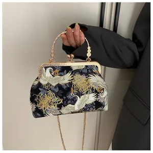 Dettaglio di una borsa vintage con intricati ricami di gru e motivi floreali dorati.