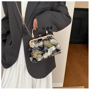 Dettaglio del ricamo di gru e crisantemo sulla borsa pochette vintage a guscio