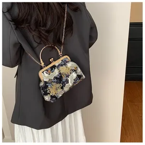 Dettaglio borsa vintage ricamata con gru e catena dorata, indossata con blazer