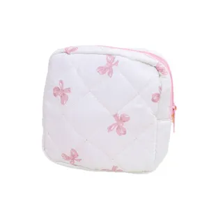 White quilted cosmetic bag with pink bow print, cute zipper pouch for makeup, data cables.