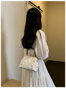 Modella con borsa a conchiglia ricamata in stile cinese con manico in bambù e motivi floreali