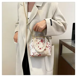Detailed view of an embroidered floral silk handbag with pearl handle and chain strap for Hanfu